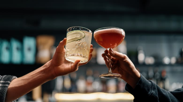 Two hands toasting with cocktails