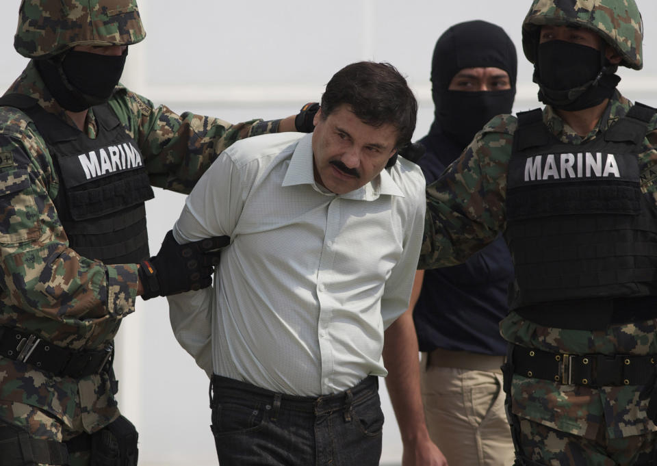 In this Saturday, Feb. 22, 2014 photo, Joaquin "El Chapo" Guzman is escorted to a helicopter in handcuffs by Mexican navy marines at a navy hanger in Mexico City, Mexico. Guzman, the head of Mexico's Sinaloa Cartel, was captured overnight in the beach resort town of Mazatlan. (AP Photo/Eduardo Verdugo)