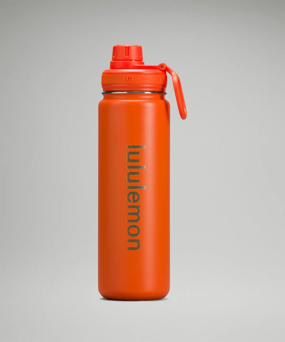 A bright orange Lululemon Back to Life Sport Bottle with logo written down the side.