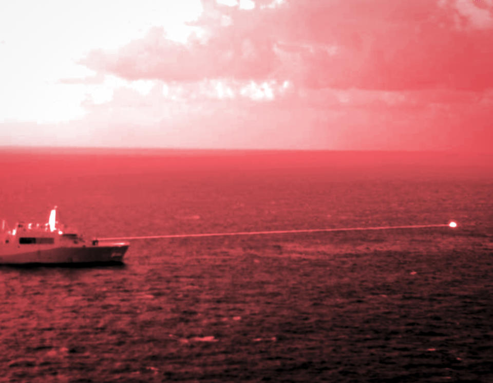 In this handout infrared photo from the U.S. Marine Corps, the USS Portland fires a laser weapon system at a target floating in the Gulf of Aden on Tuesday, Dec. 14, 2021. The U.S. Navy announced Wednesday it tested a laser weapon and destroyed a floating target in the Mideast, a system that could be used to counter bomb-laden drone boats deployed by Yemen's Houthi rebels in the Red Sea. (Staff Sgt. Donald Holbert/U.S. Marine Corps via AP)