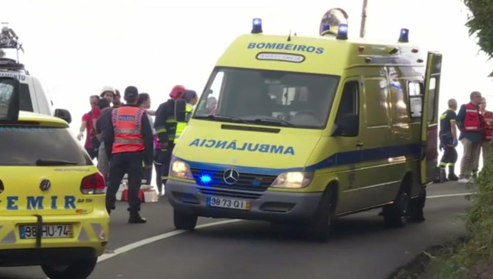 In this image from video, emergency services attend the scene after a tour bus crashed at Canico, on Portugal's Madeira Island, Wednesday April 17, 2019. Some 28 people are reported to have died in the crash, most of them German tourists, local mayor Filipe Sousa told TV news. (TVI via AP)