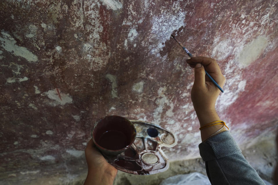 Valeria Lopez restores a mural at the 1550s-era convent of Tepoztlan in Morelos state, Mexico, Friday, Oct. 7, 2022. Indigenous symbols were found painted next to Roman Catholic motifs at this convent near Mexico City. (AP Photo/Marco Ugarte)