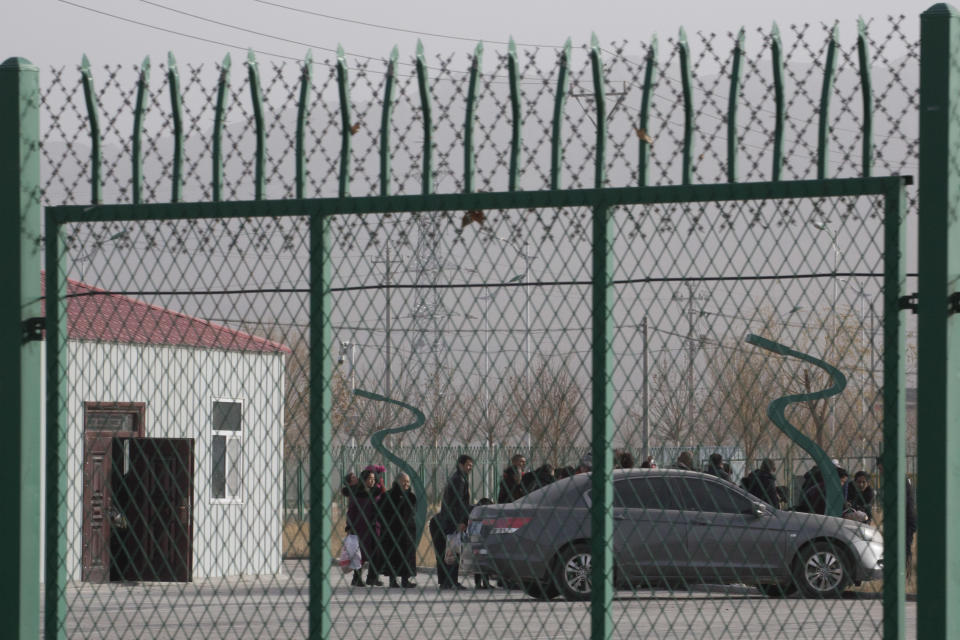 FILE - In this Dec. 3, 2018, file photo, people line up at the Artux City Vocational Skills Education Training Service Center at the Kunshan Industrial Park in Artux in western China's Xinjiang region. The Associated Press has found that the Chinese government is carrying out a birth control program aimed at Uighurs, Kazakhs and other largely Muslim minorities in Xinjiang. China’s repression in Tibet, the status of the exiled Dali Lama, and its treatment of ethnic minorities spurred violent protests ahead of Beijing’s 2008 Olympics. It could happen again. China is host to the 2022 Winter Olympics with rumblings of a boycott and calls to remove the games from Beijing because of widespread human rights violations.(AP Photo/Ng Han Guan, File)