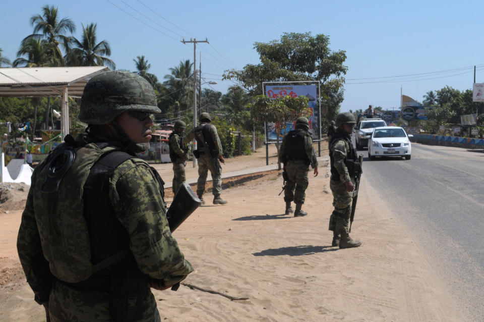 Navy marines stand at a roadblock due to stepped up security after masked armed men broke into a beach home, raping six Spanish tourists who had rented the house in Acapulco, Mexico, Tuesday Feb. 5, 2013. According to the Mayor of Acapulco, five masked men burst into a house the Spaniards had rented on the outskirts of Acapulco, in a low-key area near the beach, and held a group of six Spanish men and one Mexican woman at gunpoint, while they raped the Spanish women before dawn on Monday. (AP Photo/Bernandino Hernandez)