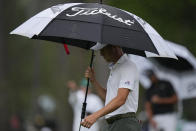 Justin Thomas protects himself from the rain as we walks on the 15th hole during the third round of the Masters golf tournament on Saturday, April 10, 2021, in Augusta, Ga. (AP Photo/Matt Slocum)