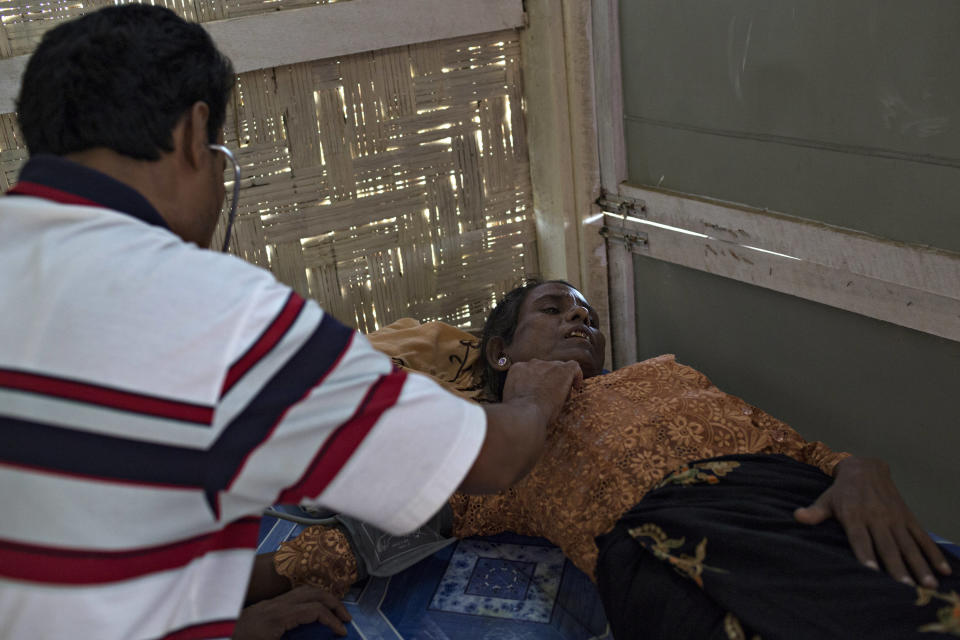 SITTWE, BURMA - MAY 06: A Rohingya medic, checks a woman's heartbeat at a clinic in the Thet Kae Pyin refugee camp. Offering limited expertise, Nar Alam does what he is able, but is not a medical doctor and can only prescribe a small quantity of medecine on May 6, 2014 in Sittwe, Burma. Some 150,000 Rohingya IDP (internally displaced people) are currently imprisoned in refugee camps outside of Sittwe in Rakhine State in Western Myanmar. Medecins Sans Frontieres (MSF), the primary supplier of medical care within the camps, was banned in March by the Myanmar government. Follow up attacks by Buddhist mobs on the homes of aid workers in Sittwe put an end to NGO operations in the camps. Though some NGOs are beginning to resume work, MSF remains banned, and little to no healthcare is being provided to most Rohingya IDPs. One Rohingya doctor is servicing 150,000 refugees with limited medication. Several Rakhine volunteer doctors sporadically enter the camps for two hours a day. Births are the most complicated procedures successfully carried out in the camps, requests to visit Yangon or Sittwe hospitals for life threatening situations require lengthy applications and are routinely denied. Malnutrition and diarrhea are the most widespread issues, but more serious diseases like tuberculosis are going untreated and could lead to the rise of drug resistant tuberculosis (DR-TB).  (Photo by Andre Malerba/Getty Images)