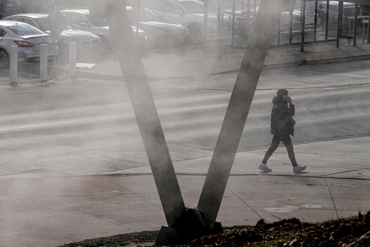 Feb 24, 2023; Columbus, Ohio, USA;  As steam rises from the sidewalk, a student walks across Cannon Drive on Ohio State’s campus. Temperatures dropped nearly 40 degrees from Thursday to Friday. Mandatory Credit: Adam Cairns-The Columbus Dispatch