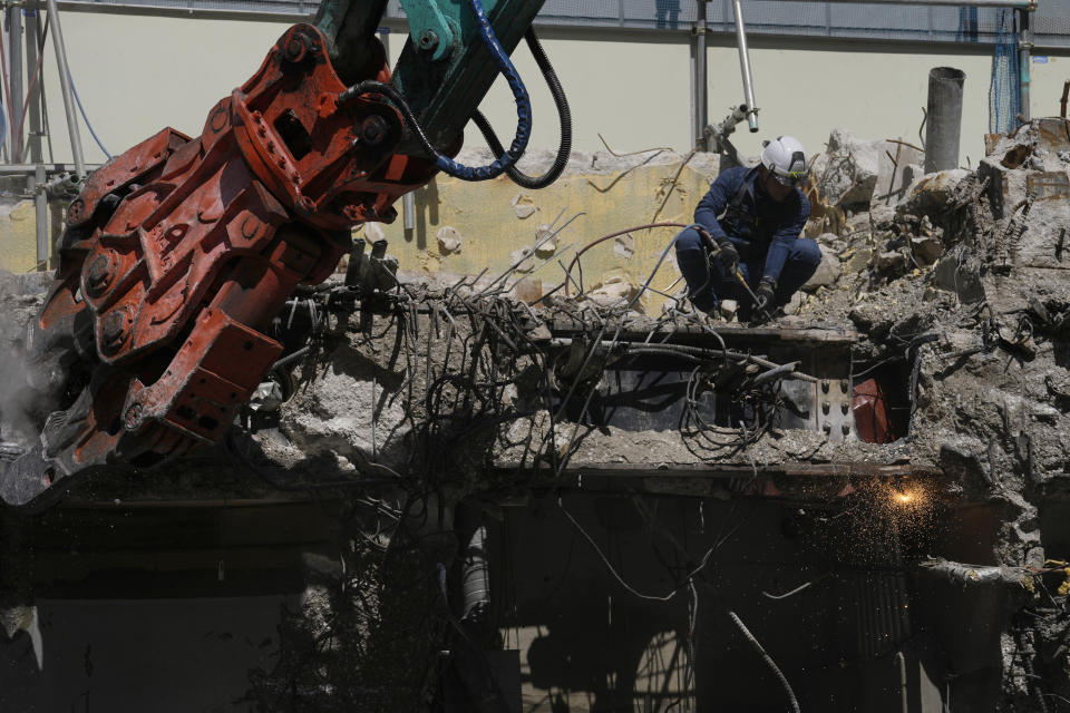 Men work at the site of the Nakagin Capsule Tower, a capsule hotel n the Ginza district, as parts of the hotel were being demolished, in Tokyo on April 8, 2022. It’s now being demolished in a careful process that includes preserving some of its 140 capsules, to be shipped to museums around the world. (AP Photo/Hiro Komae)