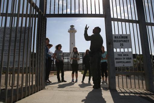 Un agente fronterizo estadounidense habla con visitantes que llegan a la valla entre su país y México, en el Parque de la Amistad, el 17 de noviembre de 2013 en San Diego, California (Getty/AFP/Archivos | John Moore)