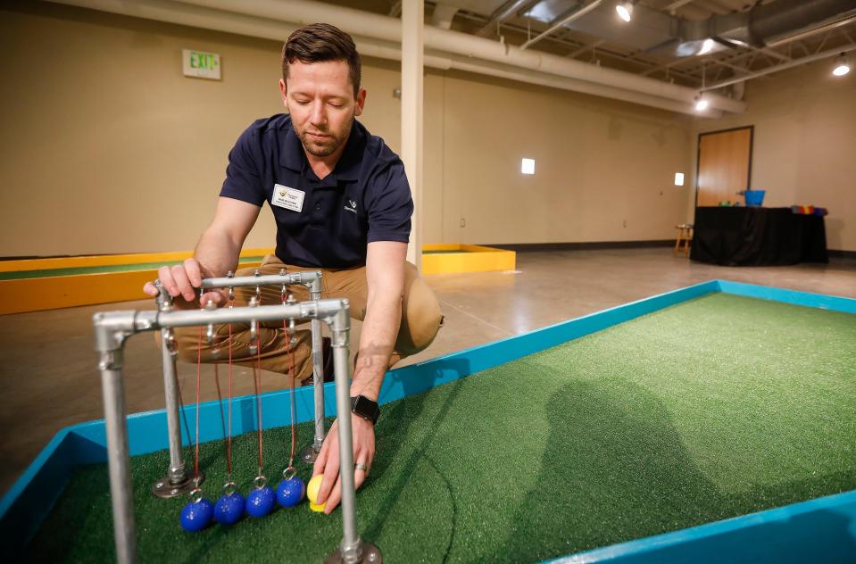 Rob Blevins, executive director at the Discovery Center, sets up the ball in front of a Newton's cradle at the new 9-hole indoor miniature golf course at the science museum. The new exhibit opens to the public on Sunday, March 31, 2019.