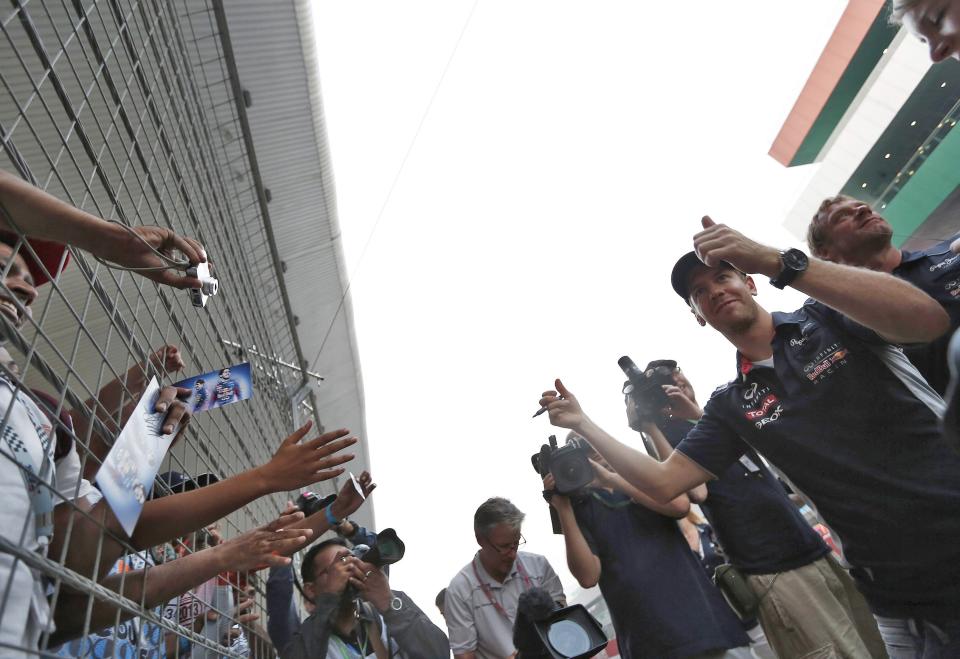 Red Bull Formula One driver Sebastian Vettel (2nd R) of Germany gestures to his fans at the Buddh International Circuit in Greater Noida on the outskirts of New Delhi October 24, 2013. The Indian F1 Grand Prix will take place from October 25-27. REUTERS/Adnan Abidi (INDIA - Tags: SPORT MOTORSPORT F1)