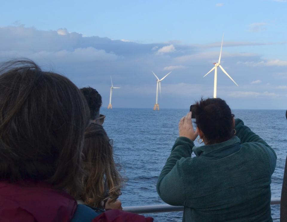 A ferry passenger on a tour of the nation's first offshore wind farm takes a photo of the turbines off Block Island.