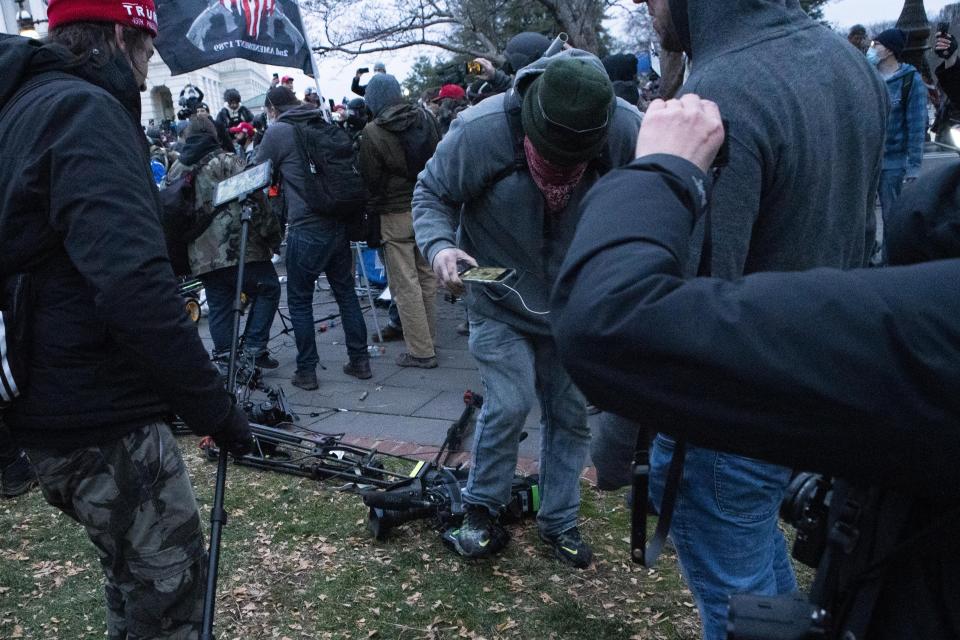 Demonstrators break TV equipment outside the the U.S. Capitol on Wednesday, Jan. 6, 2021, in Washington. (AP Photo/Jose Luis Magana)