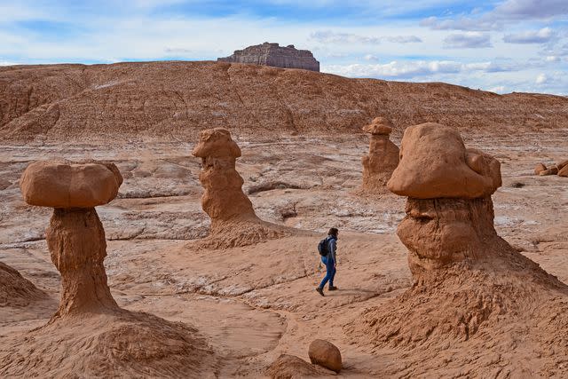 <p>Dermot Conlan/Getty Images</p> Hiker among rock formations in Goblin Valley State Park.