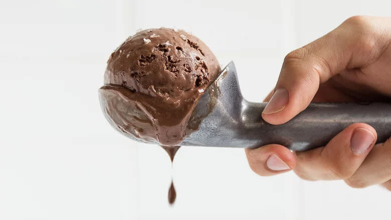 hand holding scooper with chocolate ice cream