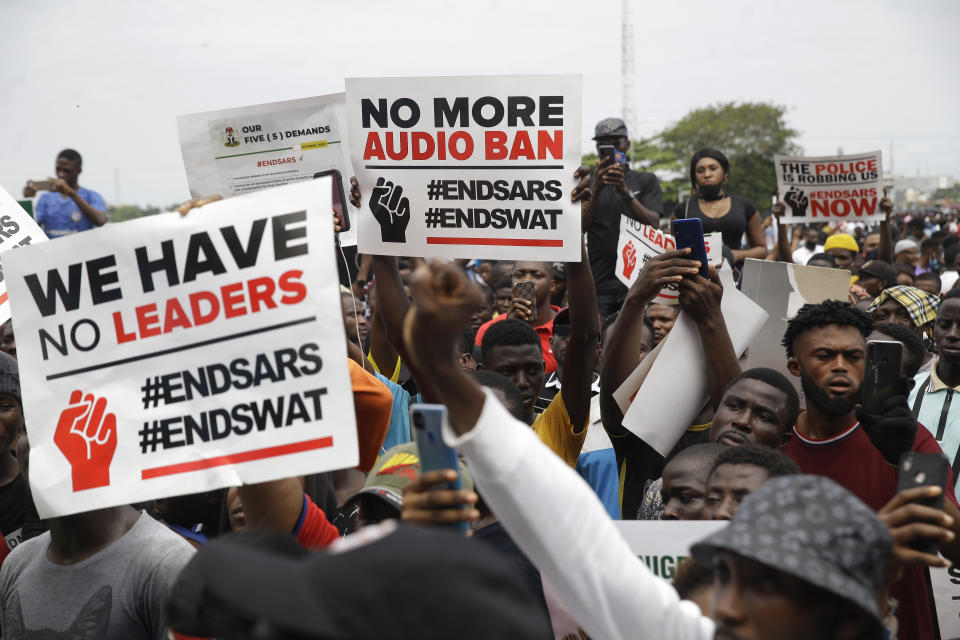 People hold banners as they demonstrate on the street to protest against police brutality in Lagos, Nigeria, Thursday Oct. 15, 2020. Protests against Nigeria's police continued to rock the country for the eighth straight day Thursday as demonstrators marched through the streets of major cities, blocking traffic and disrupting business. (AP Photo/Sunday Alamba)