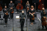 Guest conductor Esa Pekka Salonen, front center, greets a live audience as New York Philharmonic musicians stand behind him before they performed together for the first time since March 10, 2020, at The Shed in Hudson Yards, Wednesday, April 14, 2021, in New York. Normal subscription performances are scheduled to resume in September. (AP Photo/Kathy Willens)