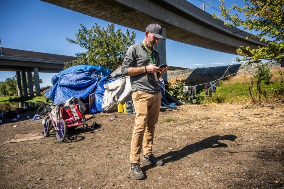 Benjamin Worrall, social services manager for the City of Sacramento Department of Community Response, takes a call along Morrison Creek near the Meadowview area on Thursday. Worrall and his team were doing outreach to a homeless community of Hmong to inform them they have to move because of potential flooding. The city is trying to find a place they can stay together.