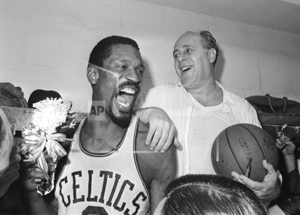 Boston Celtics' Bill Russell, left, holds a corsage sent to the dressing room as he celebrates with Celtics coach Red Auerbach after defeating the Los Angeles Lakers, 95-93, to win their eighth-straight NBA Championship, in Boston, in this April 29, 1966, photo. The NBA great Bill Russell has died at age 88. His family said on social media that Russell died on Sunday, July 31, 2022. Russell anchored a Boston Celtics dynasty that won 11 titles in 13 years. (AP Photo/File)