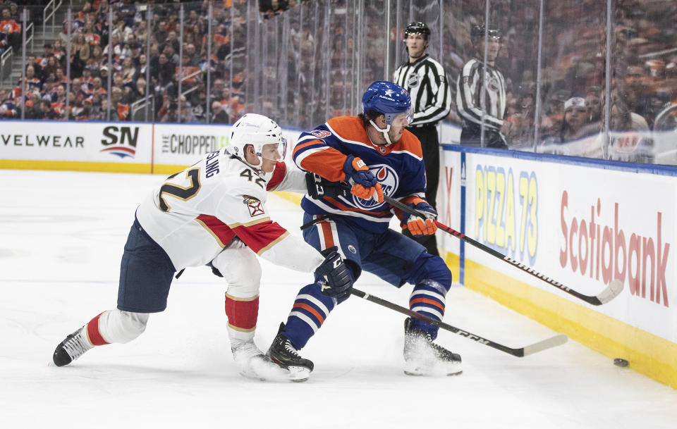 Florida Panthers defenseman Gustav Forsling (42) and Edmonton Oilers' Mattias Janmark (13) battle for the puck during the second period of an NHL hockey match in Edmonton, Alberta, on Saturday Dec. 16, 2023. (Jason Franson/The Canadian Press via AP)