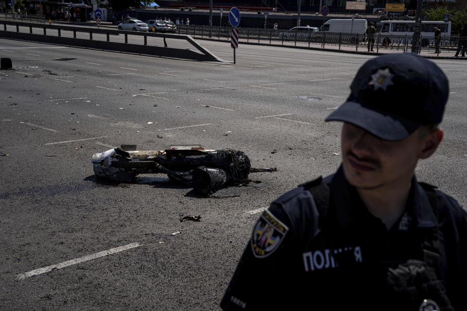 A Ukrainian police officer guards a fragment of the rocket after a Russian rocket attack in Kyiv, Ukraine, Monday, May 29, 2023. Explosions have rattled Kyiv during daylight as Russian ballistic missiles fell on the Ukrainian capital. The barrage came hours after a more common nighttime attack of the city by drones and cruise missiles. (AP Photo/Evgeniy Maloletka)
