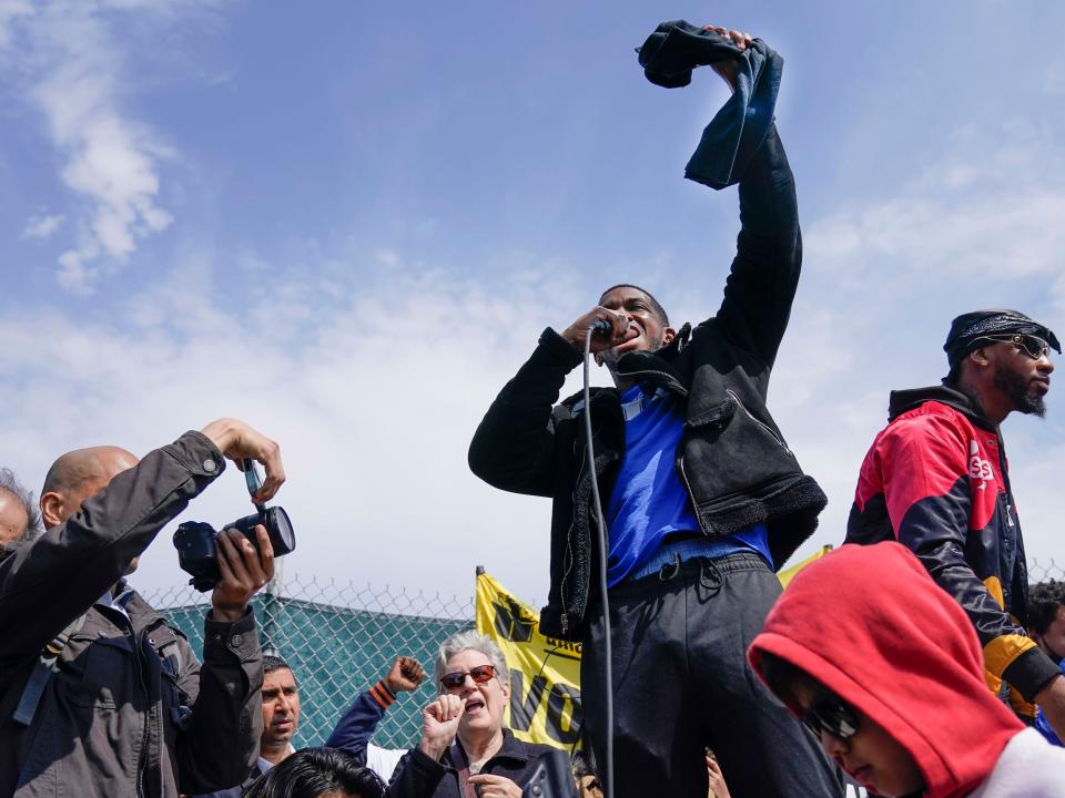 Amazon Labor Union vice president Derrick Palmer raises a t-shirt into the air during a rally in April 2022.