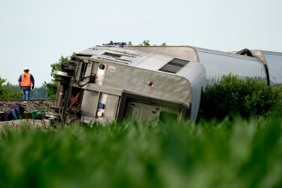 A worker inspects the scene of an Amtrak train which derailed after striking a dump truck, Monday, June 27, 2022, near Mendon, Mo. (AP Photo/Charlie Riedel)