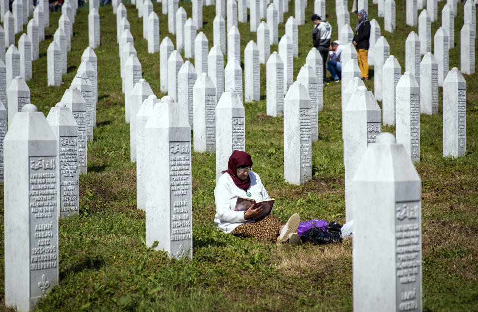 FILE - A woman reads a religious text at the memorial cemetery, prior to the funeral in Potocari, near Srebrenica, Bosnia, Thursday, July 11, 2019. Survivors of war crimes committed during Bosnia’s 1992-95 war say the victims of ongoing human rights abuses in Ukraine should learn from their experience of fighting for justice, but that they must first make peace with the fact that reaching it will inevitably be a lengthy and painful process. (AP Photo/Darko Bandic, File)