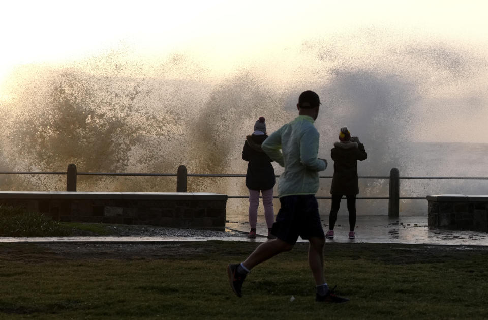 Waves break over Sea Point's promenade in Cape Town, South Africa, Monday, July 8, 2024. City authorities say nearly 1,000 homes in informal settlements around the city have been destroyed by gale-force winds, displacing around 4,000 people with multiple cold fronts expected until at least Friday. (AP Photo/Nardus Engelbrecht)