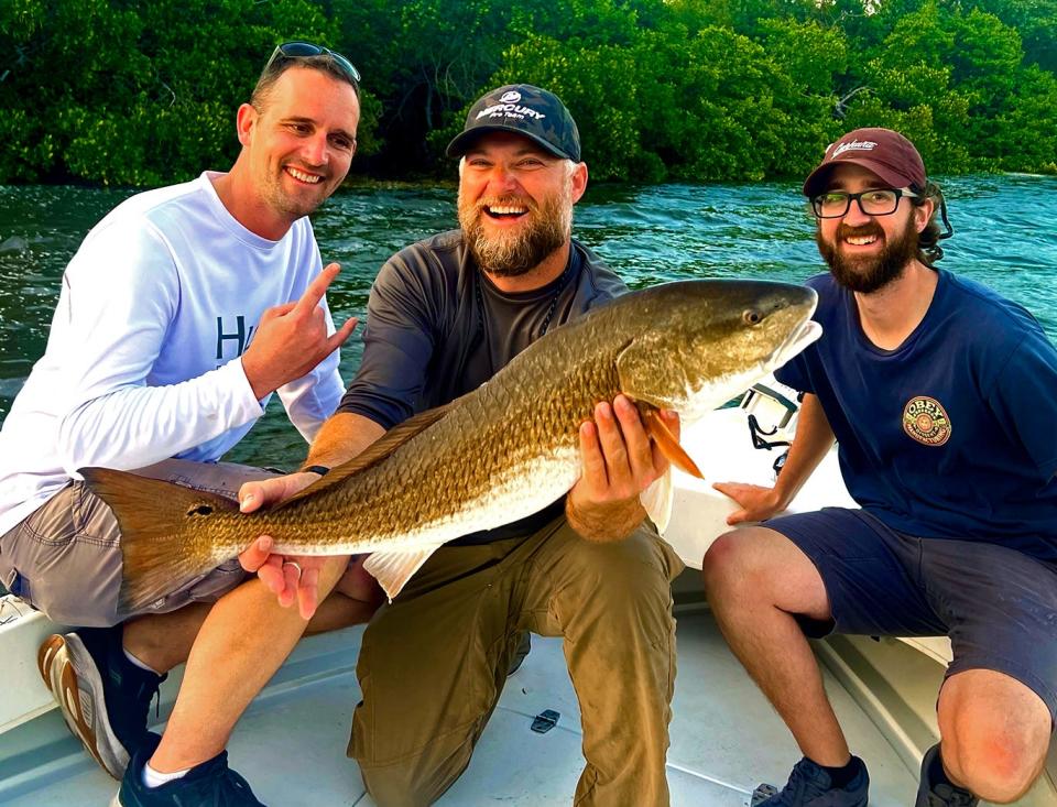 Capt. Neill Holland, center, of St. Petersburg, along with clients Jared Arlinghaus, left, and Caleb Christ, show off an over slot size redfish they caught while fishing in St. Petersburg this week.