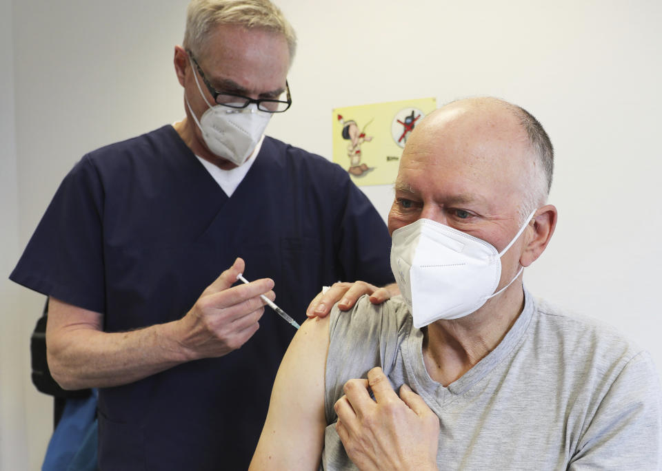 Manfred Haas, right, receives the AstraZeneca vaccine against the COVID-19 disease from his family doctor Oliver Funken in Rheinbach, Germany, Tuesday, April 6, 2021. In German federal state North Rhine-Westphalia, Corona vaccinations have started in GP surgeries. (Oliver Berg/dpa via AP)