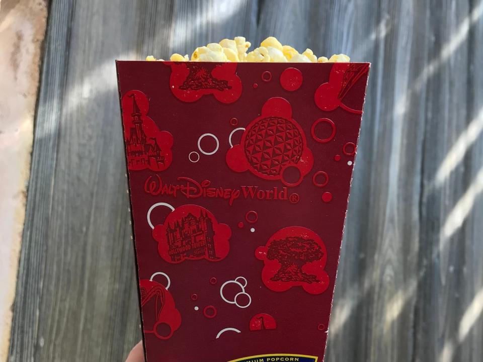 hand holding up a container of popcorn at disney world