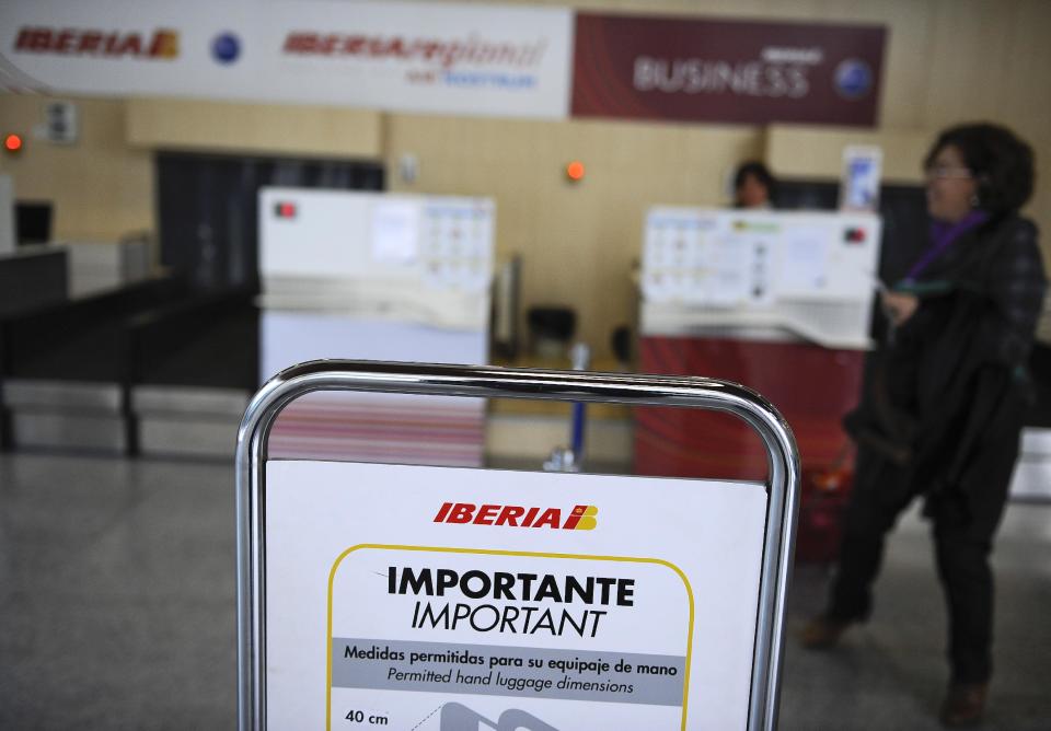 A notice sign for Iberia airline advising passengers on permitted hand luggage dimensions is seen next to check-in counters at Noain airport, near Pamplona, northern Spain, Friday, Nov. 9, 2012. International Airlines Group warned on Friday that its Spanish carrier Iberia was "in a fight for survival" and unveiled a restructuring plan to cut 4,500 jobs as it reported a drop in third-quarter profit. (AP Photo/Alvaro Barrientos)