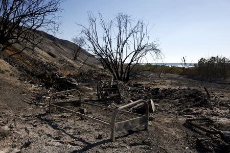 A burnt bed frame stands in a makeshift encampment in the aftermath of a wildfire in the Solimar Beach area of Ventura County, California December 26, 2015. REUTERS/Patrick T. Fallon