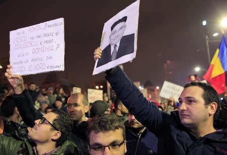 A man holds a picture depicting Romania's Prime Minister Victor Ponta as North Korean leader Kim Jong-un during a rally in Bucharest, in support of Romanians living abroad who were turned away from voting in the first round of the presidential election, November 14, 2014. REUTERS/Radu Sigheti