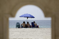 People sit on Hollywood Beach during the new coronavirus pandemic, Thursday, July 2, 2020, in Hollywood, Fla. In hard-hit South Florida, beaches from Palm Beach to Key West will be shut down for the Fourth of July holiday weekend. (AP Photo/Lynne Sladky)