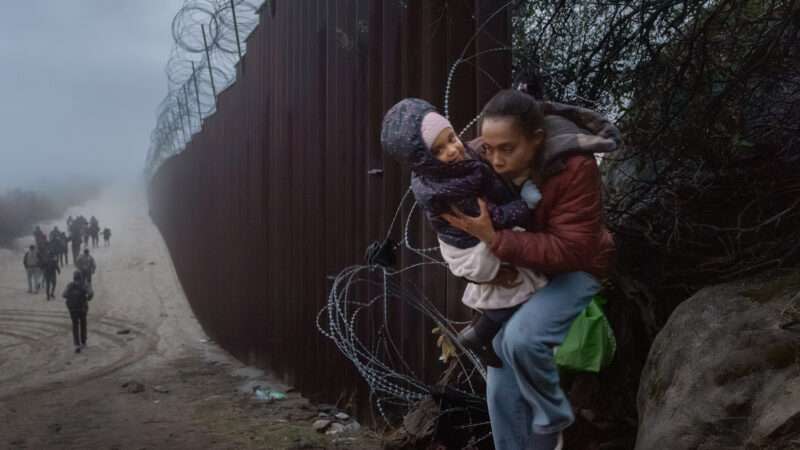 Migrants pictured along the U.S.-Mexico border fence