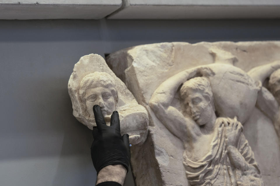 FILE - An Acropolis Museum staff places a marble male head on a frieze of the Acropolis museum, one of three fragments from the ancient Parthenon temple that have been returned to Greece by the Vatican museums, in Athens, Friday, March 24, 2023. Italy, a long time victim of antiquities theft that has worked for decades to recover its treasures, is coming to terms with the fact that it, too has stolen loot in its museum collections: the relics of a brutal colonial empire that the country hasn't fully reckoned with. (AP Photo/Petros Giannakouris, File)