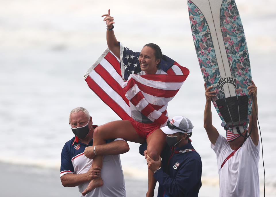 Moore sitting on the shoulders of coaches with a flag draper around her shoulders to celebrate winning the Gold Medal after her final match