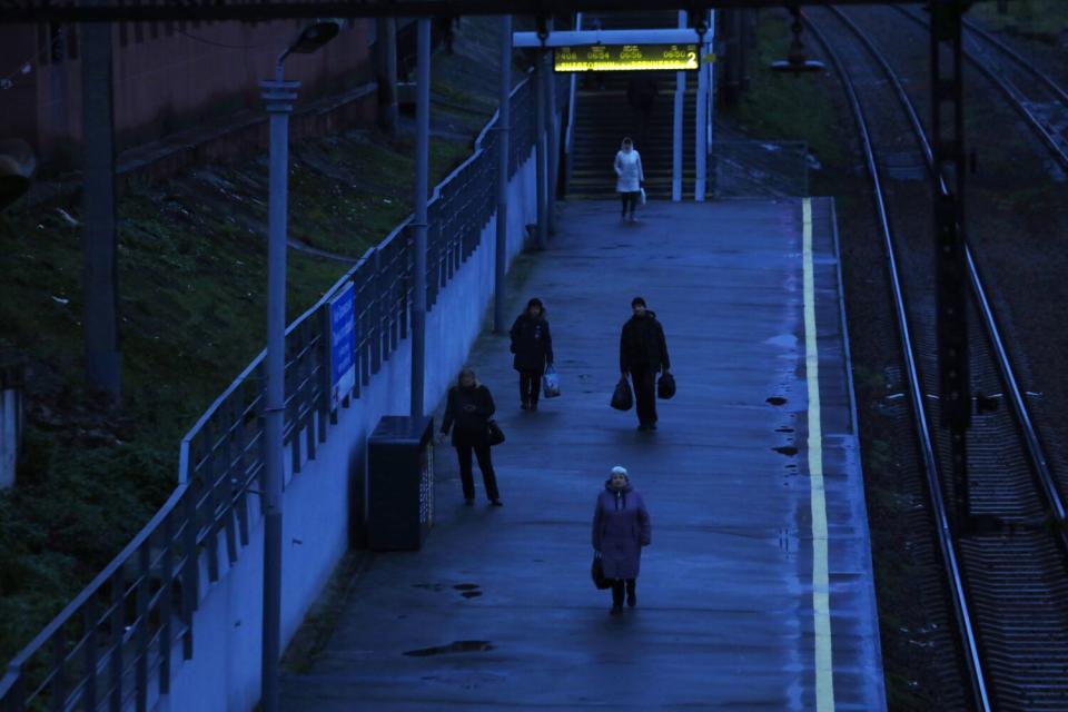 Several people standing on a dimly lit train platform