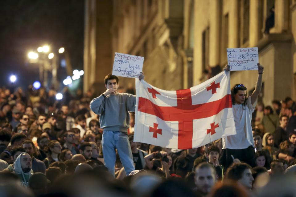 Demonstrators hold a Georgian national flag as they gather outside the parliament building in Tbilisi, Georgia, on Wednesday, April 17, 2024, to protest against "the Russian law" similar to a law that Russia uses to stigmatize independent news media and organizations seen as being at odds with the Kremlin. (AP Photo/Zurab Tsertsvadze)