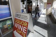 In this photo taken Wednesday, March 25, 2020, a shopper leaves a liquor store in Seattle. Many, if not most, liquor stores in Washington state are considered "essential businesses" and can stay open under Gov. Jay Inslee's stay-at-home order issued Monday in the midst of the coronavirus outbreak. (AP Photo/Elaine Thompson)