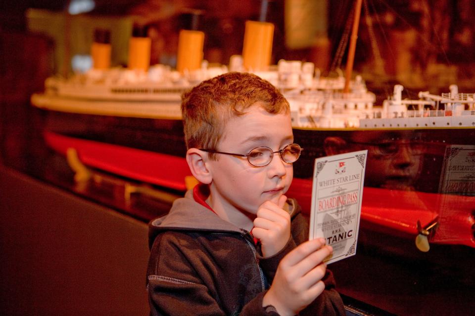A boy examines a boarding pass from the Titanic.