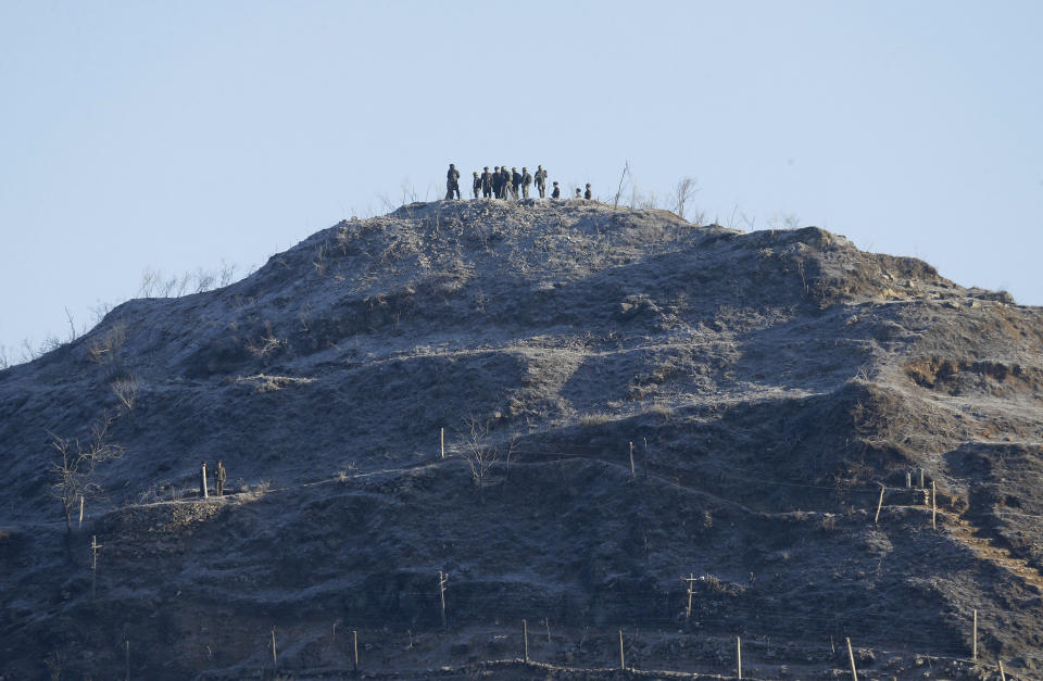 South, wearing yellow head bands, and North Korean army soldiers inspect the dismantled North Korean guard post inside the Demilitarized Zone (DMZ) in the central section of the inter-Korean border in Cheorwon, Wednesday, Dec. 12, 2018. South Korea and North Korea have removed some of their guard posts along the border as part of their military agreement last September. (AP Photo/Ahn Young-joon, Pool)