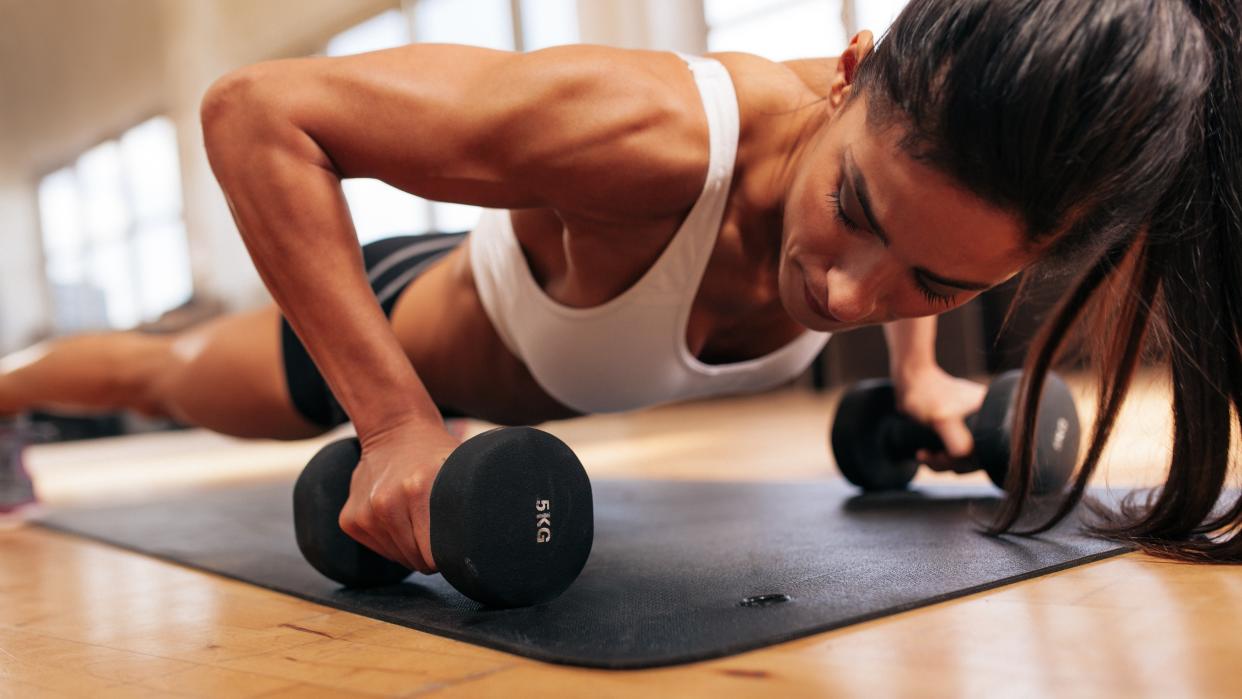  a photo of a woman doing a push-up with dumbbells 