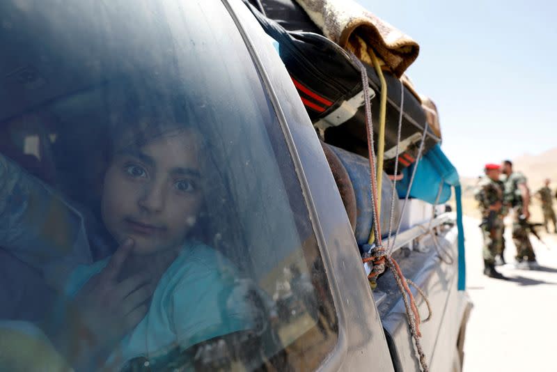 FILE PHOTO: A Syrian refugee girl who left Lebanon looks through a window as she arrives in Qalamoun