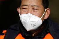 A village committee member wears face mask and vest as he guards at the entrance of a community to prevent outsiders from entering, as the country is hit by an outbreak of the new coronavirus, in Tianjiaying village, outskirts of Beijing
