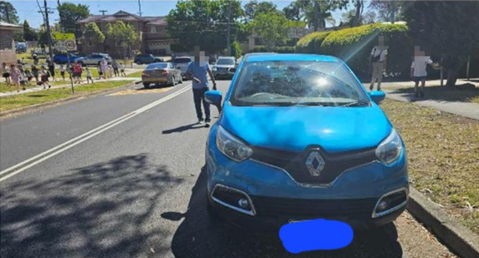 Blue car parked on Sydney street close to the dividing line. 