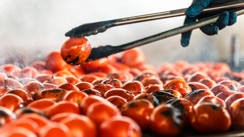 Tongs holding grilled tomato