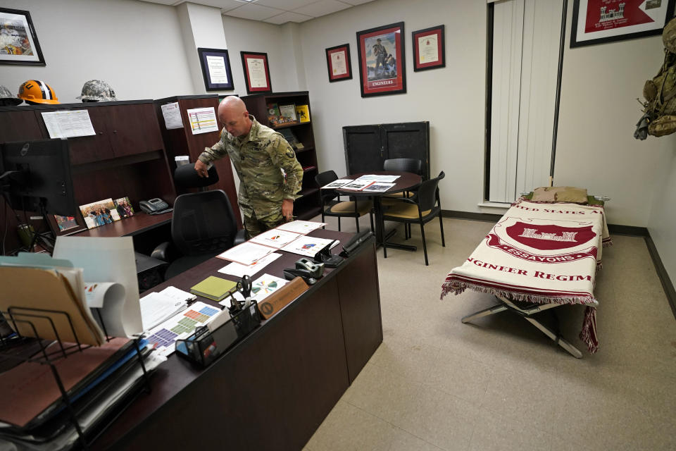 Capt. Michael Switzer goes to sit at his desk before he goes to sleep in his office at Camp Beauregard in Pineville, La., Friday, July 30, 2021. (AP Photo/Gerald Herbert)